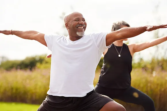 Happy Black man with arms outstretched celebrating outdoors during exercise, embodying wellness and healthy living for National Wellness Month